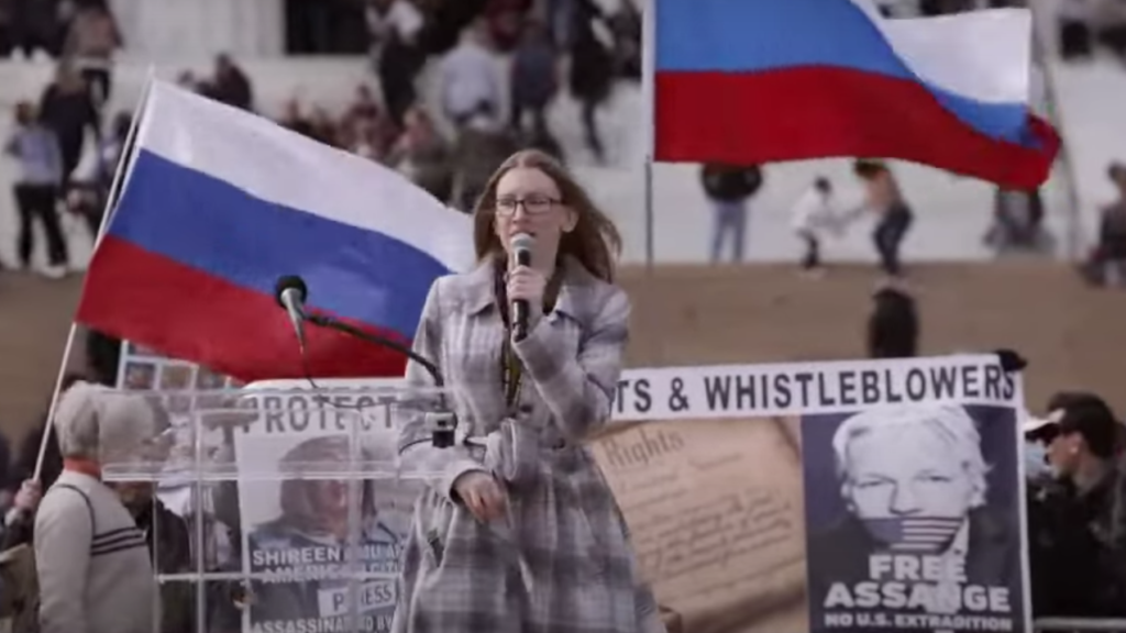 Libertarian Party Chair Angela McArdle speaking before Russian flags. (Libertarian Party on YouTube)